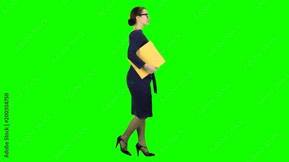 Girl is walking along the street with a folder in her hands. Green screen. Side view Girl is walking along the street with a folder in her hands. Green screen. Side view