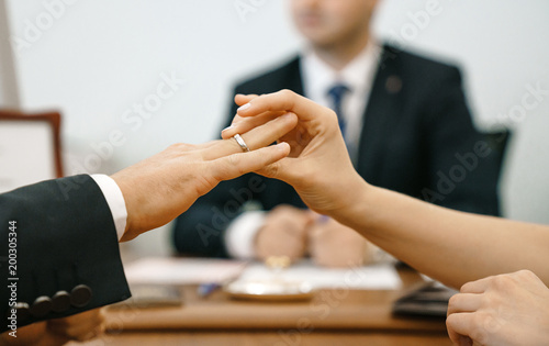 A woman puts a wedding ring in a registry office for a man. Marriage and hands close-up against the background of the ceremony master. Traditional and state violation of marriage.