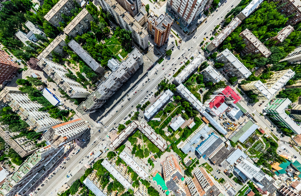 Fototapeta premium Aerial city view with crossroads and roads, houses, buildings, parks and parking lots, bridges. Helicopter drone shot. Wide Panoramic image.