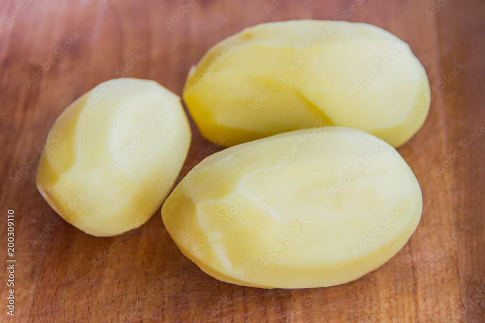 Peeled potatoes on a wooden Board, slicing and cooking fried potatoes Peeled potatoes on a wooden Board, slicing and cooking fried potatoes