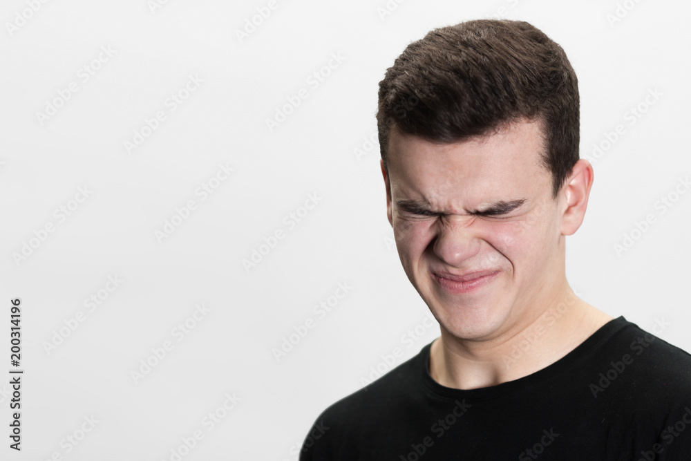 Fototapeta premium Close up of young male face looking disgusted on a white background. Isolated white background