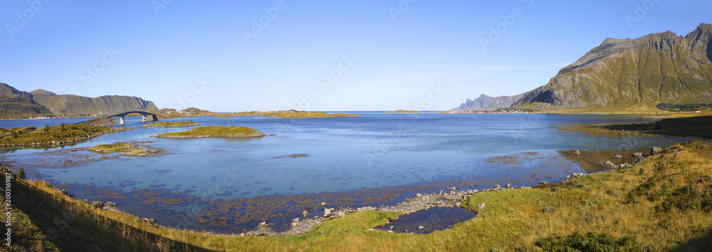 panoramic view from fredvang bridges to ramberg in autumn with mountains in backgrond and beautiful blue fjord in foreground , lofoten islands, norway