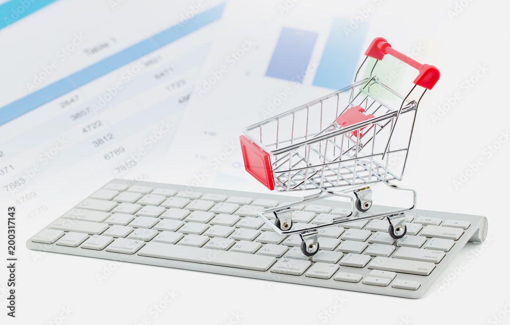 Shopping cart on white keyboard and graph show break even point, concept business