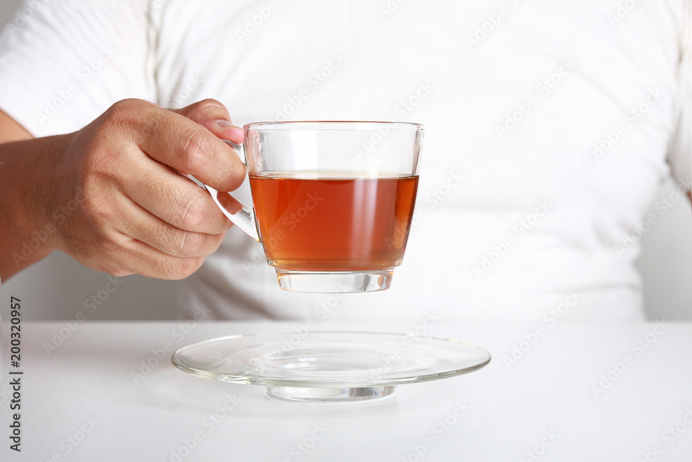 Fat man By drinking tea to lose weight. Put on a white shirt sitting on a white table. Hands holding a glass of tea. Fat man By drinking tea to lose weight. Put on a white shirt sitting on a white table. Hands holding a glass of tea.