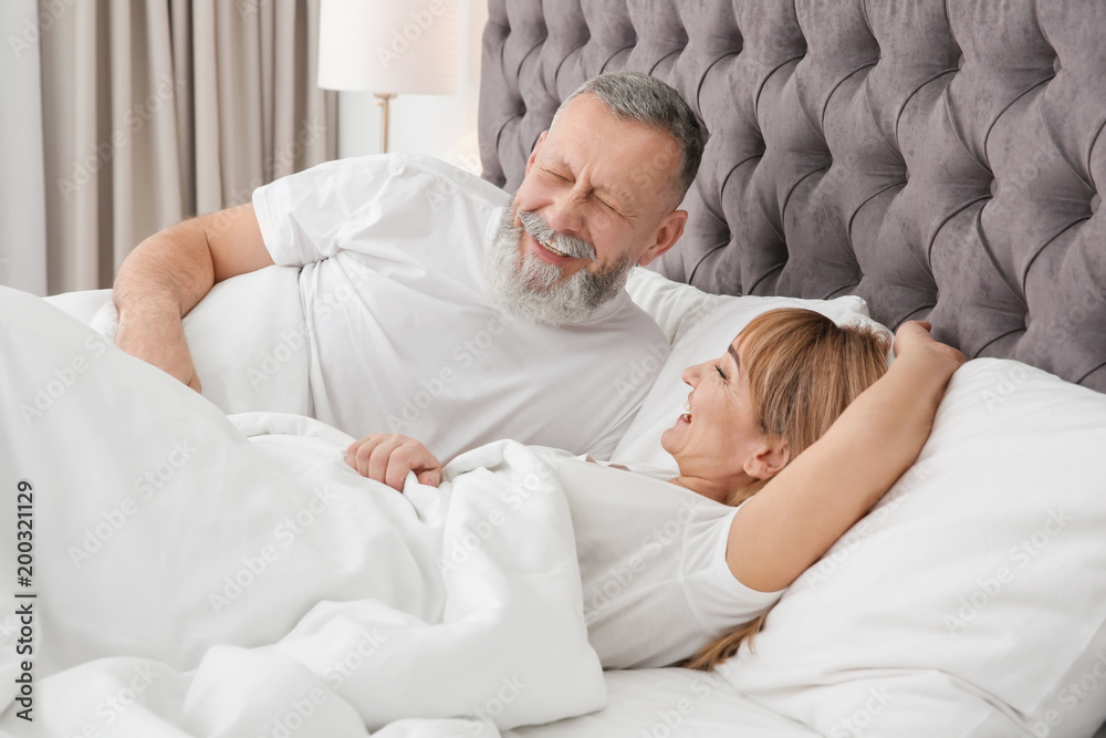 Mature couple together in bed at home Mature couple together in bed at home