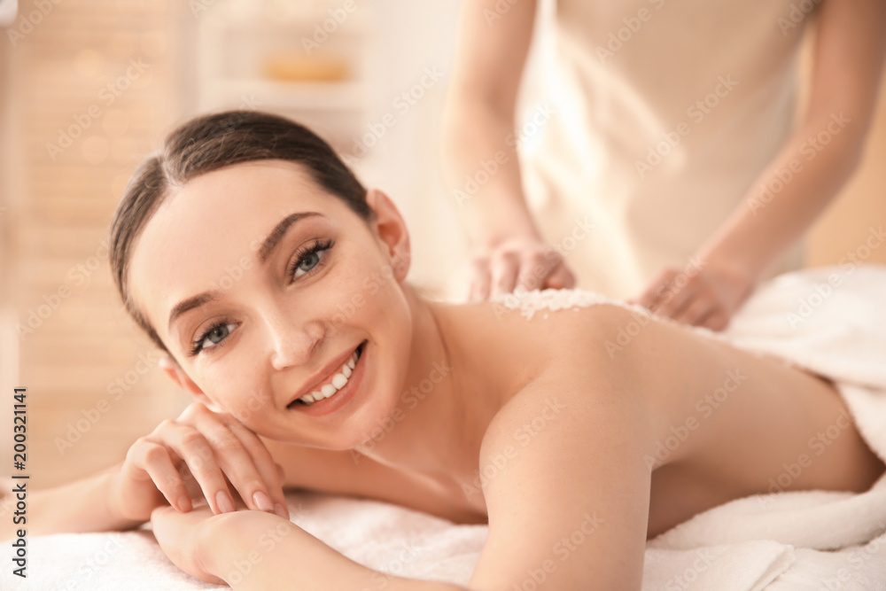 Beautiful young woman having massage with body scrub in spa salon Beautiful young woman having massage with body scrub in spa salon