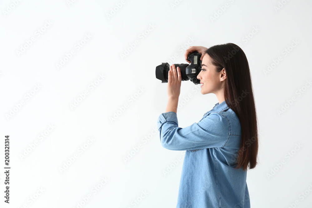 Female photographer with camera on light background Female photographer with camera on light background