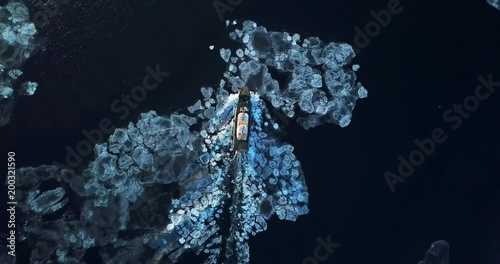 Flying above the Eastern Bosphorus strait. Aerial view of the ship slowly moving through ice floes. Others are stuck on the background. Vladivostok, Russia. Evening