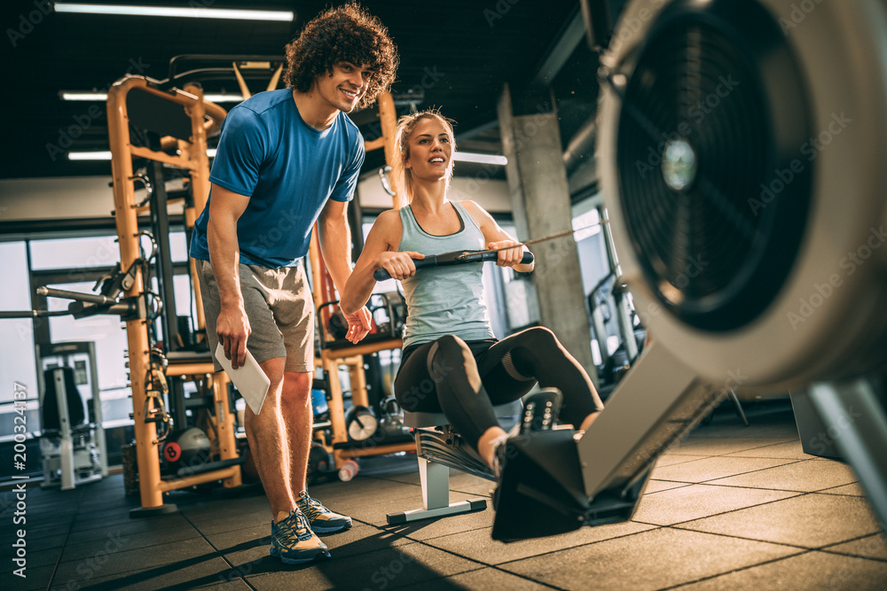Obraz premium Young girl with her personal instructor in fitness center. Having a partner makes the workout a lot easier. 