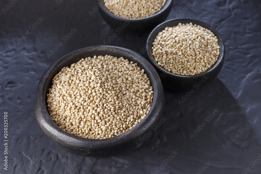 Quinoa grains with spoon and bowl on black background Quinoa grains with spoon and bowl on black background