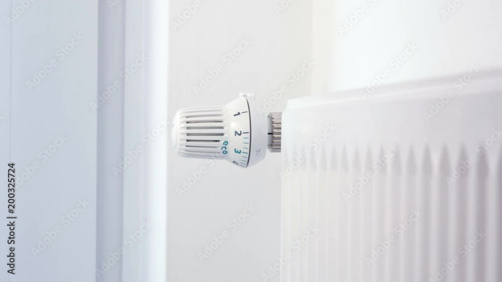 House heating - Hand turns the heating thermostat House heating - Hand turns the heating thermostat