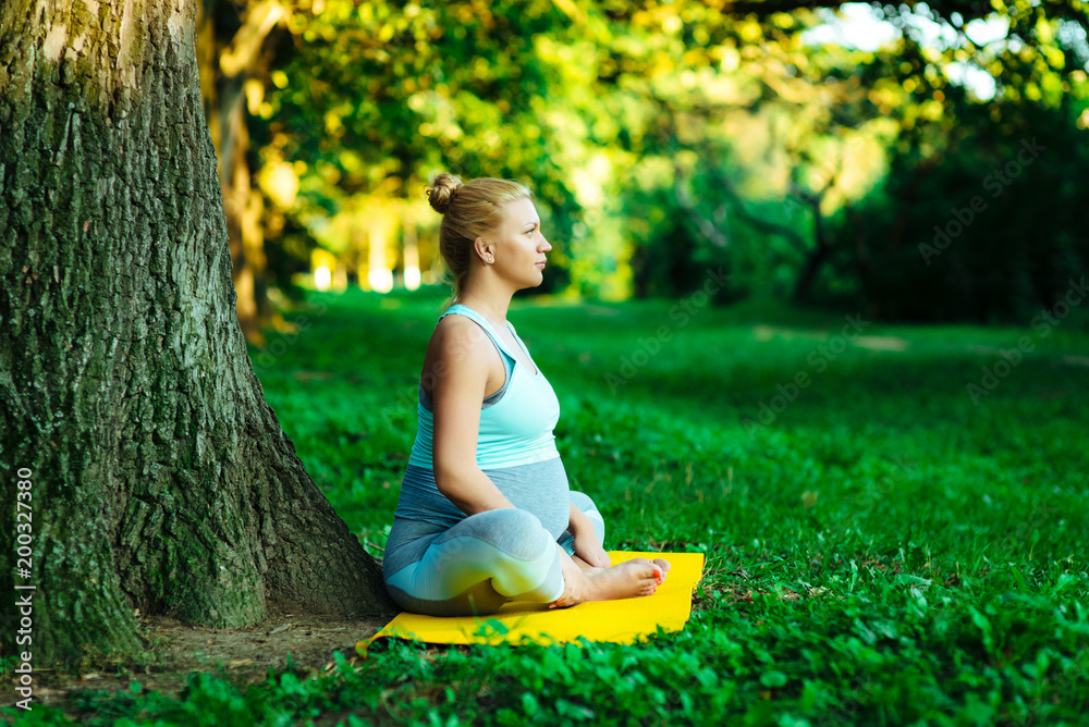 Young pregnant girl doing yoga in the park Young pregnant girl doing yoga in the park