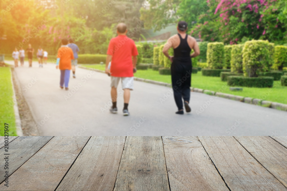 Wooden foreground with blurred public parks, People are jogging, Health and nature concept Wooden foreground with blurred public parks, People are jogging, Health and nature concept