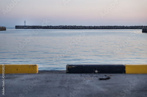 View from the harbout to white lighthouse at a seawall with wavebreakers in Seogwipo, Jeju Island, South Korea photo