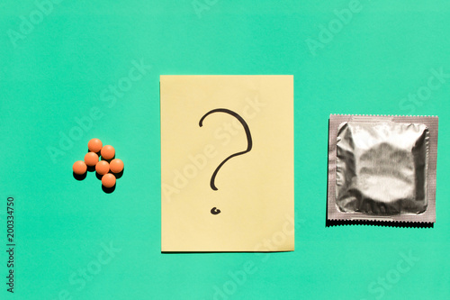 Birth control pills and condom isolated on turquoise background . The concept of choice .