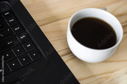 Minimalistic flat lay composition: A cup of coffee and a black keyboard, top view, close-up