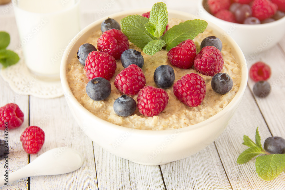 Oatmeal with raspberries.Healthy food for breakfast.Tasty oatmeal with berries in bowl on table Oatmeal with raspberries.Healthy food for breakfast.Tasty oatmeal with berries in bowl on table