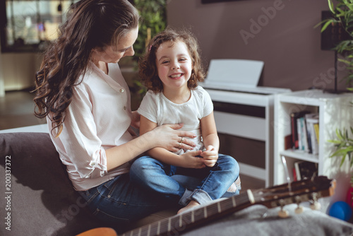 Cheerful mother and daughter relaxing in the living room