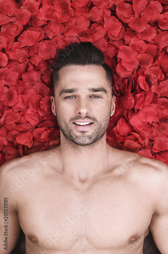 Handsome man laying on rose petals photo