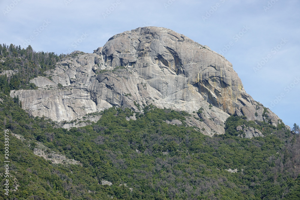 Moro Rock, a dome-shaped, granite monolith, is shown from a distant view on a spring day. The massive rock is located in the center of California's Sequoia National Park and is a popular hiking spot.