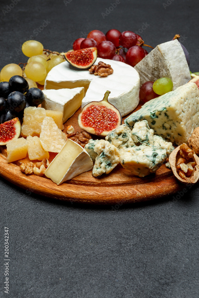 Brie cheese on a wooden Board with fresh figs and grapes Brie cheese on a wooden Board with fresh figs and grapes