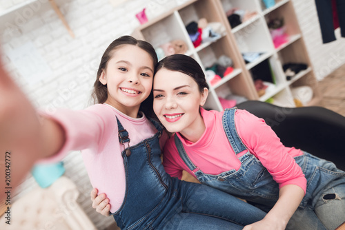 Mom with a little girl do selfie on a smartphone.