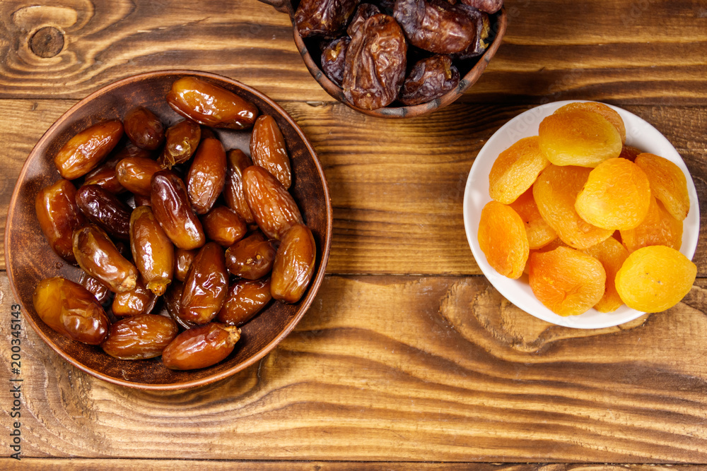 Dried apricots and dates fruit on wooden table. Top view Dried apricots and dates fruit on wooden table. Top view