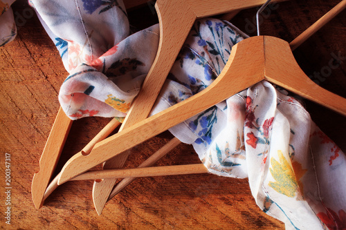 Wooden empty clothes hangers on wooden background. What nothing to wear concept. Woman clothing photo