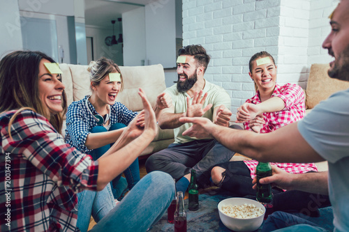 Bild auf Leinwand Happy friends playing game guess who and having fun at home