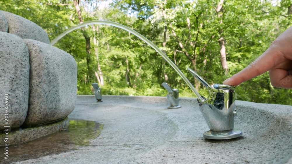 pressing a faucet on a drinking fountain in a park in Korea. pressing a faucet on a drinking fountain in a park in Korea.