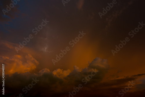 Stroke of lightning with storm clouds and golden sunset light