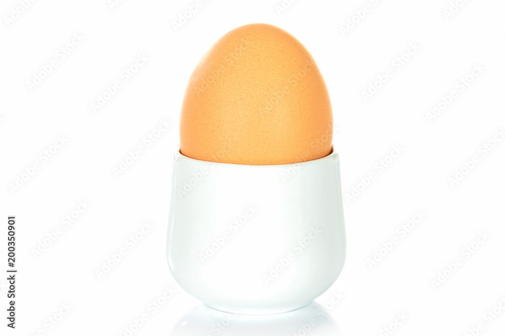 Boiled egg in an egg cup on a white background. Boiled egg in an egg cup on a white background.