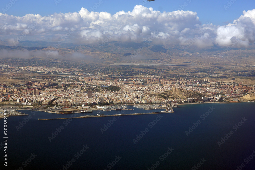 View from the height of the aircraft to the sea and coastal cities under the clouds