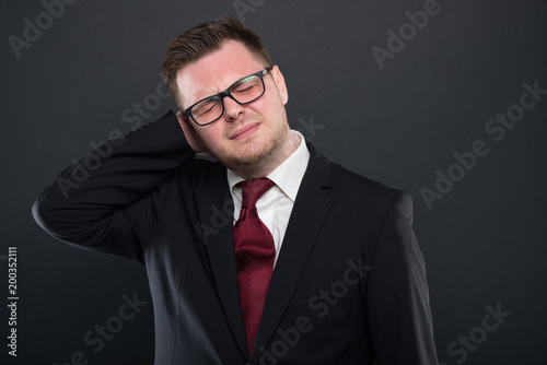 Portrait of business man wearing black suit gesturing back ache.