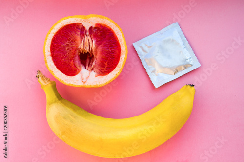 Banana and grapefruit with condom on pink background, Safe Sex Concept photo