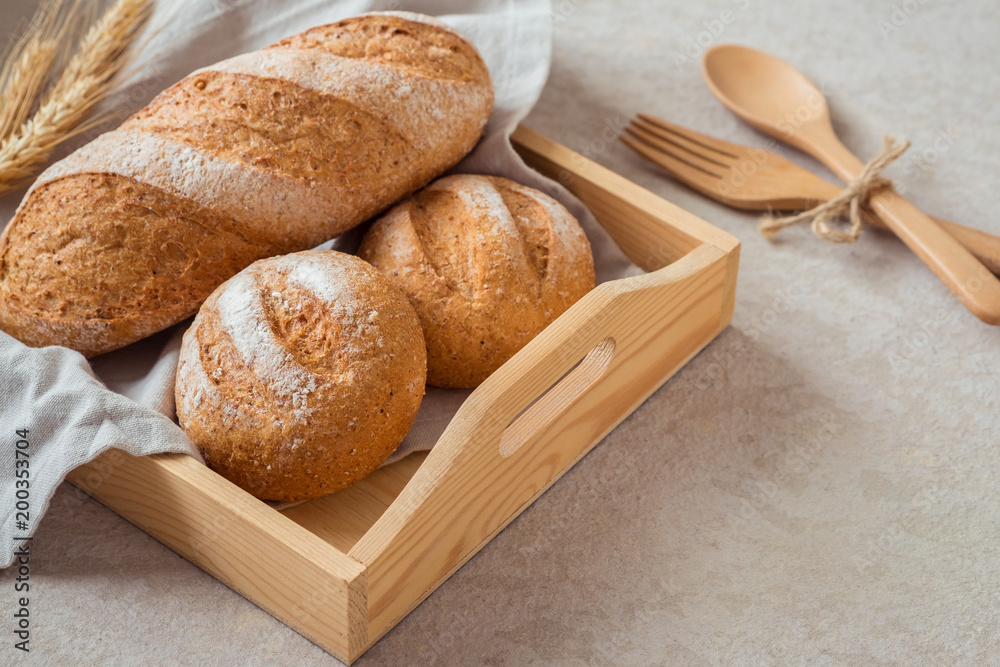 Naklejka premium Bread and buns on wooden tray .