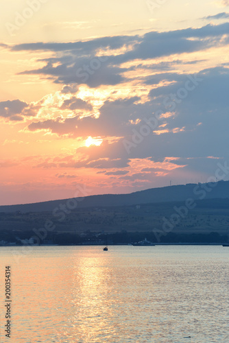 Evening scenery of sunset over the sea and mountains. Sea evening landscape with clouds