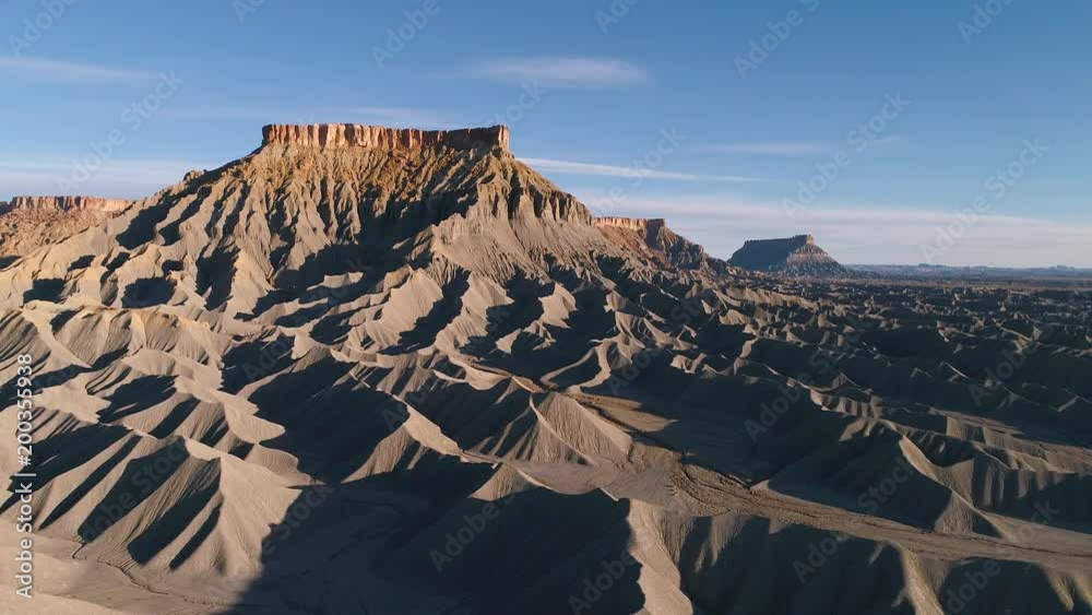 Aerial view flying towards Caineville mesa with hills of desert terrain ...