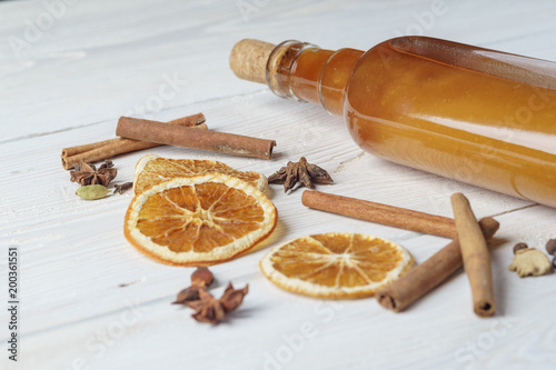 Bottle of fresh alcoholic tincture with cinnamon, pepper, orange on the bar table