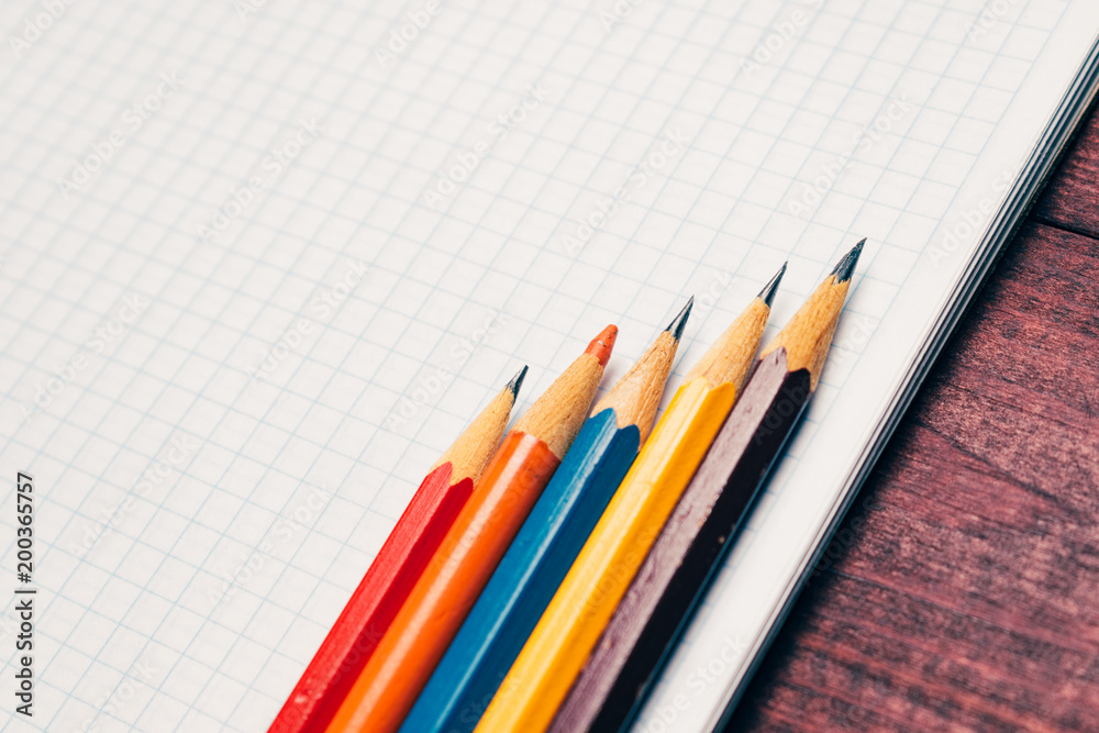 Bright used colorful pencils next to a blank sheet of paper. Work supplies stationery on a wooden texture table. Vintage minimal look. Symmetry composition. Concept of a modern freelancer workplace Bright used colorful pencils next to a blank sheet of paper. Work supplies stationery on a wooden texture table. Vintage minimal look. Symmetry composition. Concept of a modern freelancer workplace