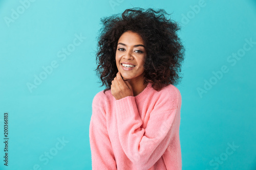 Beautiful brunette woman in pink shirt looking on camera with perfect smile, isolated over blue background
