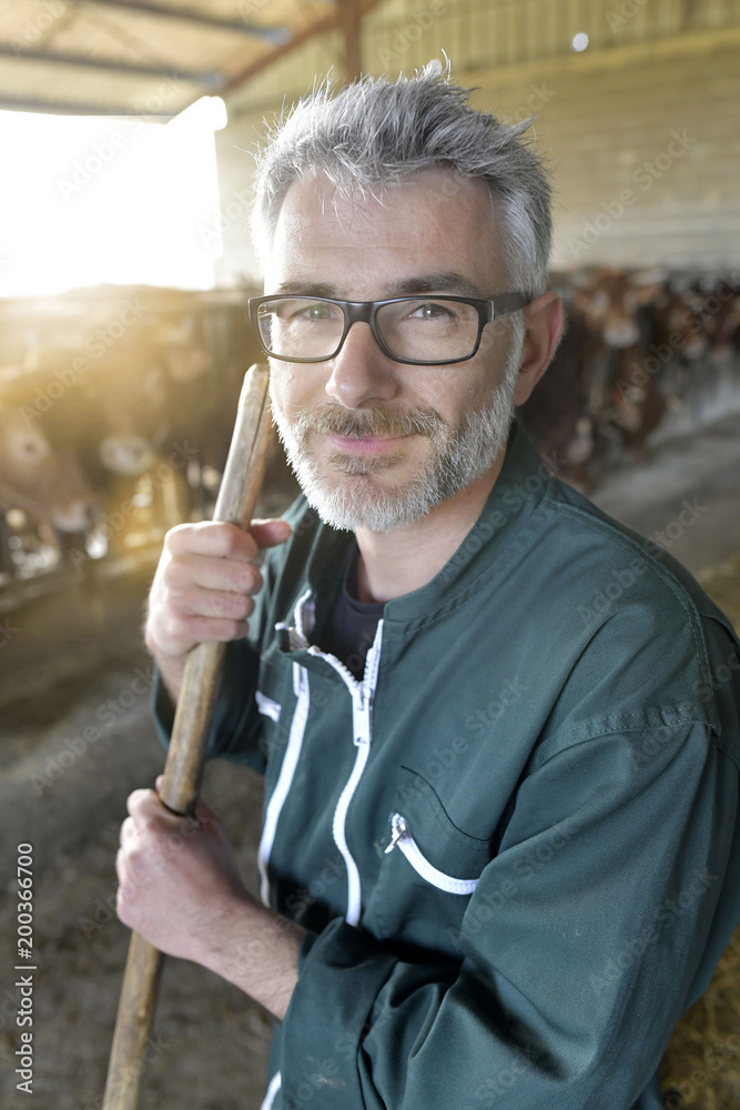 Smiling farmer standing in cow shed Smiling farmer standing in cow shed