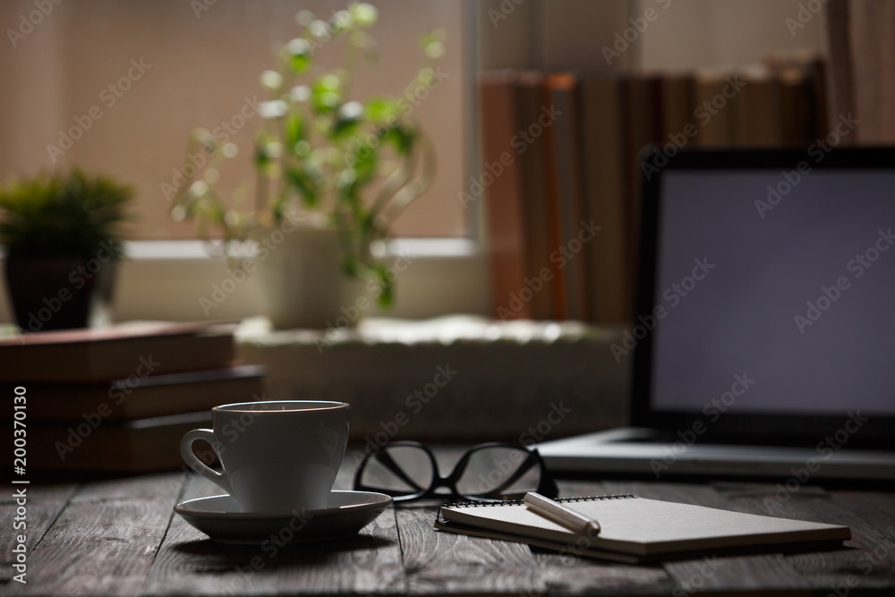 A cup of coffee in the workplace on a wooden table. A cup of coffee in the workplace on a wooden table. The concept of working outside the office A cup of coffee in the workplace on a wooden table. A cup of coffee in the workplace on a wooden table. The concept of working outside the office