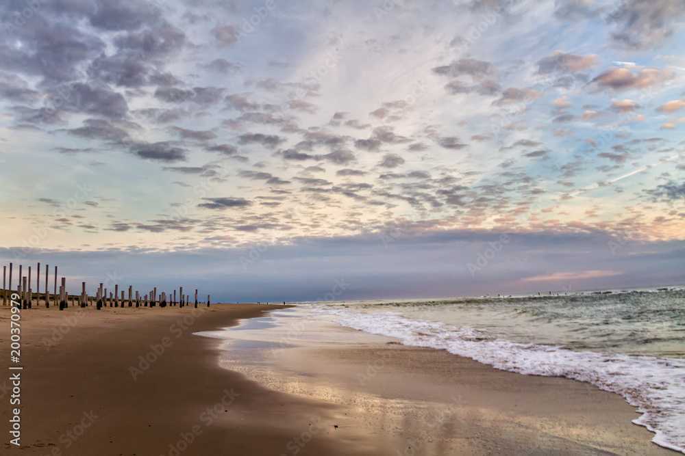 Beautiful dramatic cloudy sky over the wooden piles from the beach, Petten, Holland, North Sea