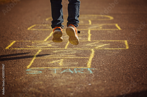 Cuadro en lienzo Kids playing hopscotch on playground outdoors