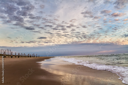 Fototapeta Naklejka Na Ścianę i Meble -  Beautiful dramatic cloudy sky over the wooden piles from the beach, Petten, Holland, North Sea