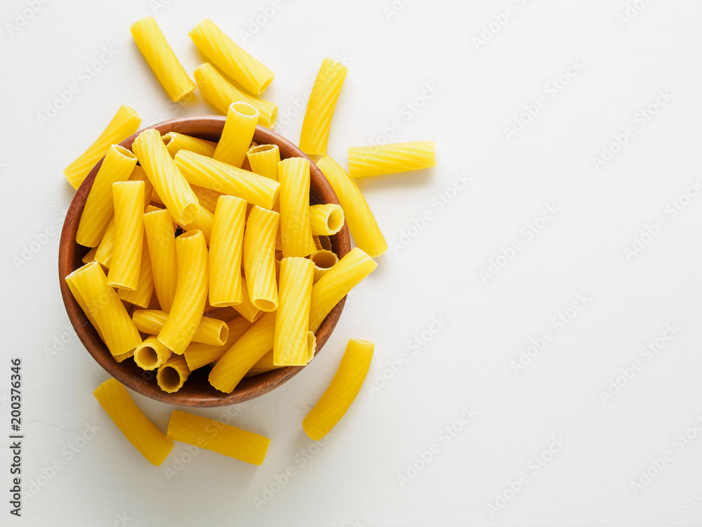 Pasta Tortiglioni in wooden bowl on gray stone table. Top view, empty place for text.