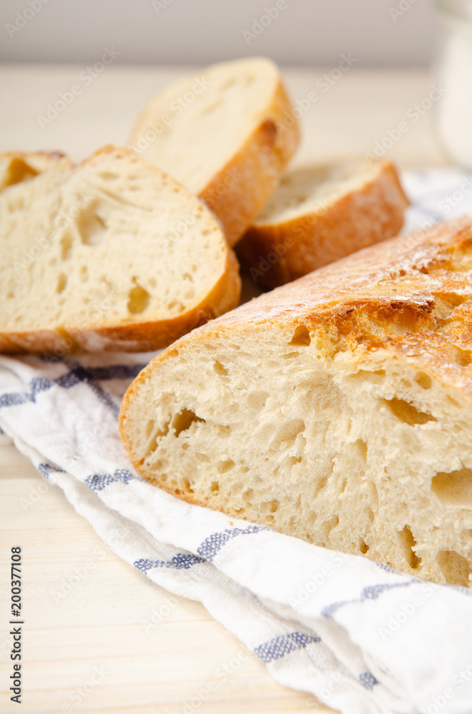 Ciabatta bread. Slices of ciabatta with garlic, salt on wooden table on white towel. Rustic style, italian. Close up, white background Ciabatta bread. Slices of ciabatta with garlic, salt on wooden table on white towel. Rustic style, italian. Close up, white background