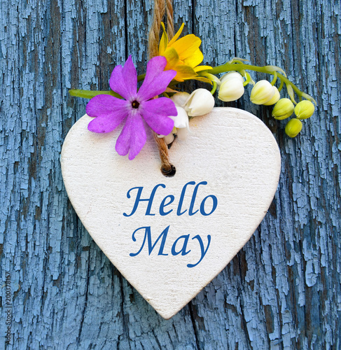 Hello May greeting card with decorative white heart and spring flowers on old blue wooden background.Springtime concept.Selective focus.