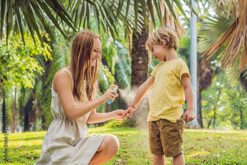 Mom and son use mosquito spray.Spraying insect repellent on skin outdoor photo